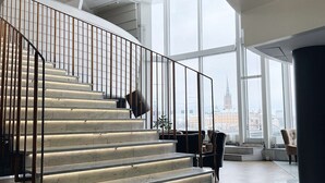 A modern interior with a marble staircase, large windows, and a view of a cityscape. - Hilton Stockholm Slussen (Stockholm)