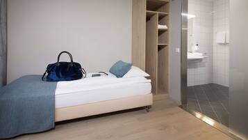 Quarto moderno com uma cama, uma mala azul e um guarda-roupa.