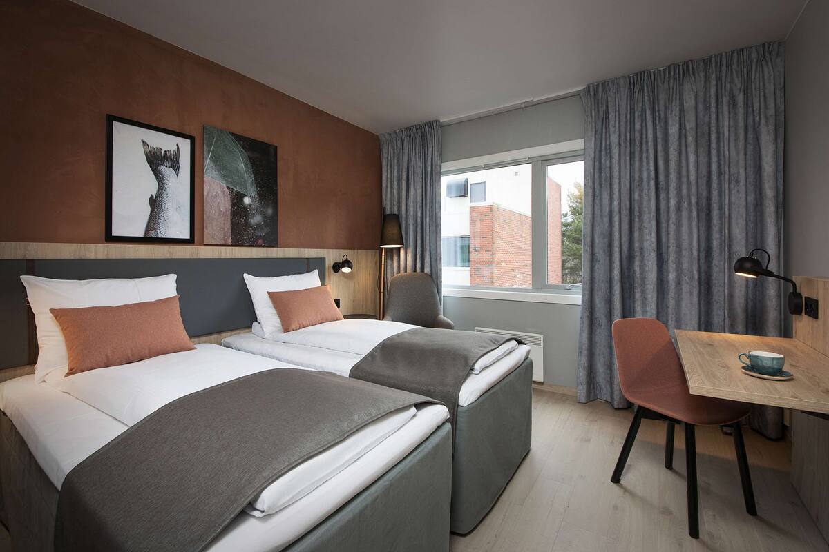 Habitación de hotel con dos camas, un escritorio y una silla.
