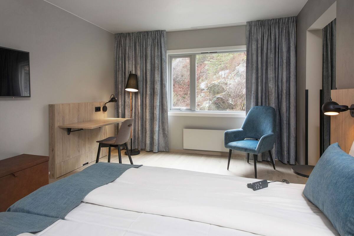 Una habitación de hotel moderna con cama, escritorio, silla y televisor.