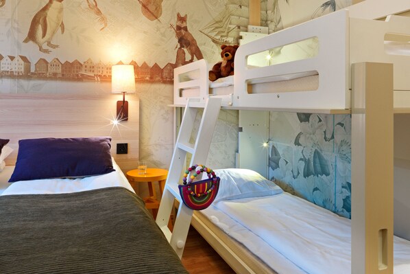 A room with bunk beds, a lamp, a teddy bear, and a map on the wall.