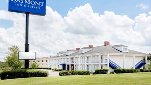 A Baymont Inn & Suites building with a large sign, multiple balconies, and a well-maintained lawn.