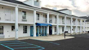 Ein Motel mit blauem Vordach, auf dem 'Baymont' steht, ein Parkplatz und ein klarer Himmel.