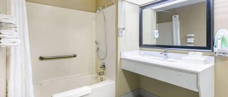 Un baño con bañera, ducha y lavamanos con espejo.