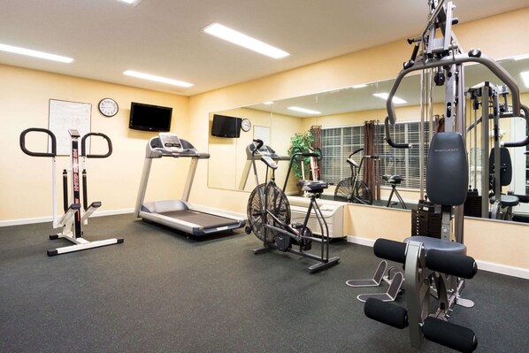 Une salle de sport équipée de tapis de course, d’un appareil elliptique et de machines de musculation.