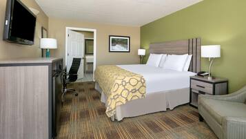 A hotel room with a bed, bedside tables, a desk, a chair, a television, and a door.