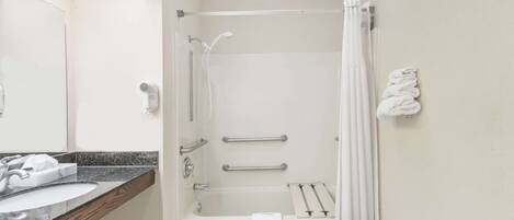 Une salle de bain équipée d’un lavabo, d’un miroir, d’un porte-serviettes, d’une douche et d’une baignoire.