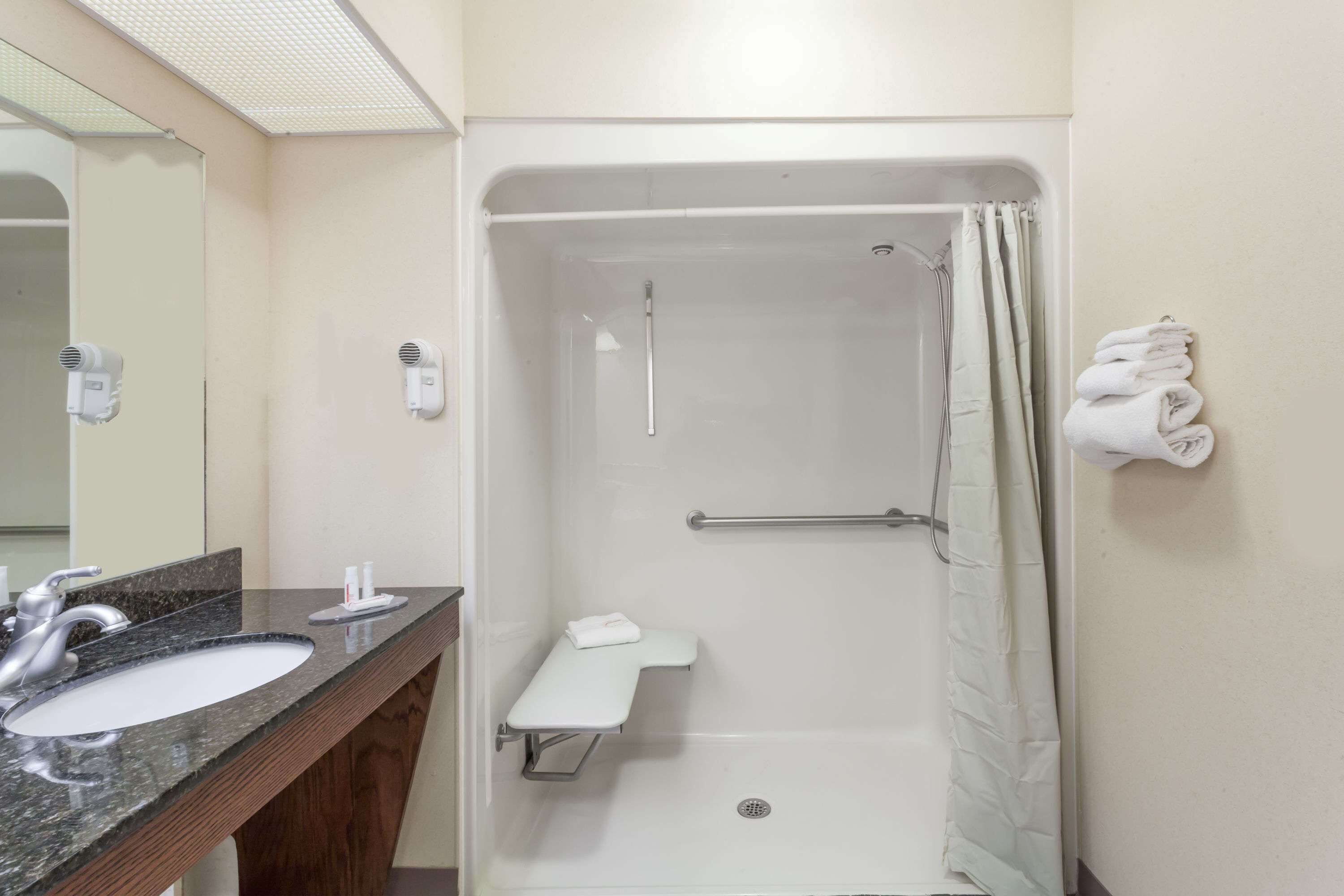 A bathroom with a sink, mirror, towel rack, and a shower with a curtain.
