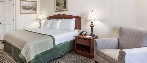 A hotel room with a bed, two bedside tables with lamps, a chair, and two framed pictures on the wall.