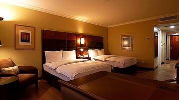 A hotel room with two beds, a desk, a chair, and a small table.
