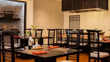 A restaurant with dark wooden furniture, a central table with a bottle of wine, and a decorative wall.
