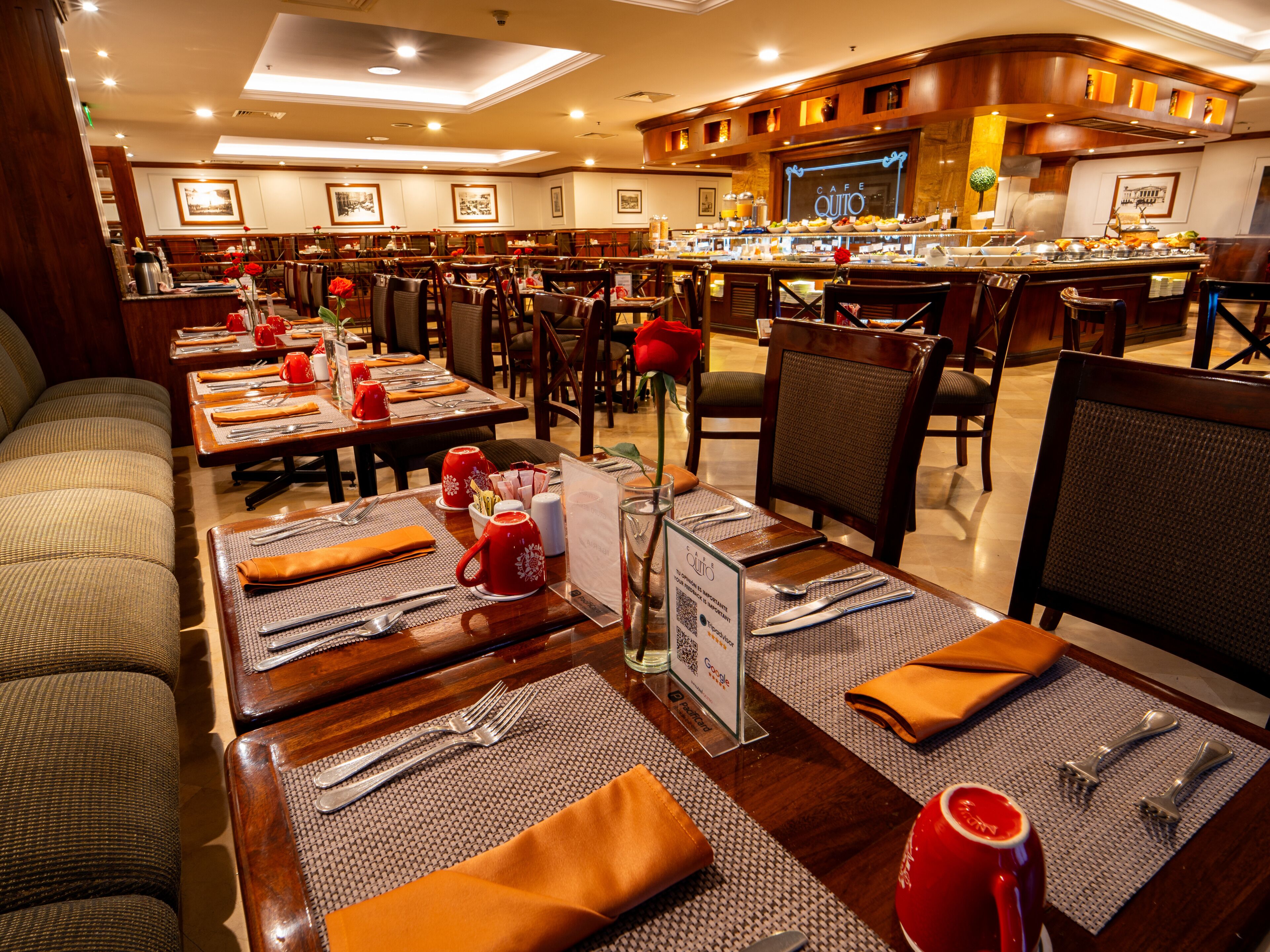 A hotel dining area with multiple tables set for guests, featuring a variety of seating options including chairs and a sofa.