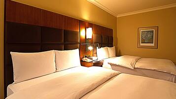 Une chambre d’hôtel avec deux lits, une tête de lit en bois, une table de chevet avec une lampe et un tableau encadré au mur.