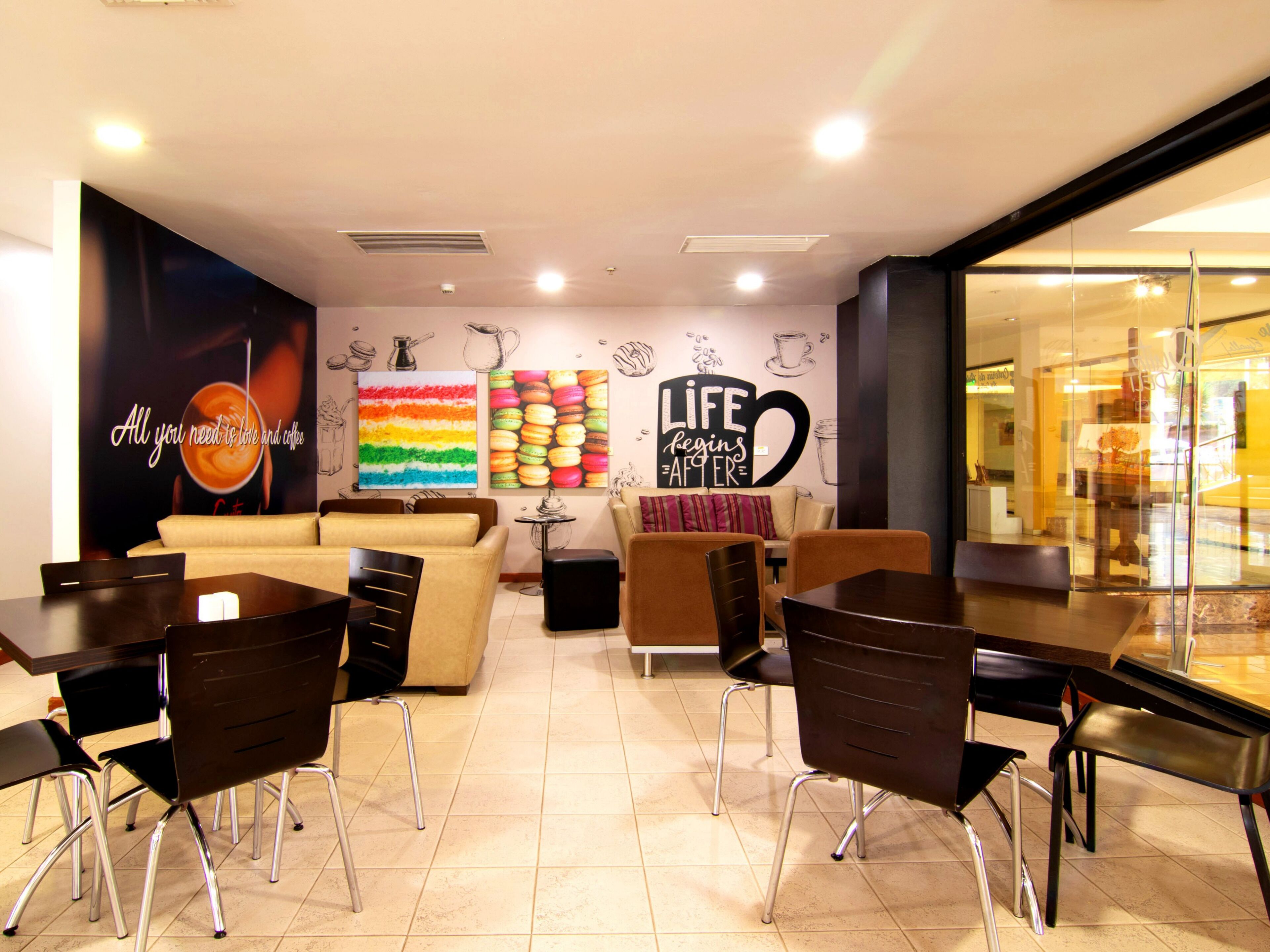 A modern cafe with a vibrant mural, comfortable seating, and a clean, tiled floor.