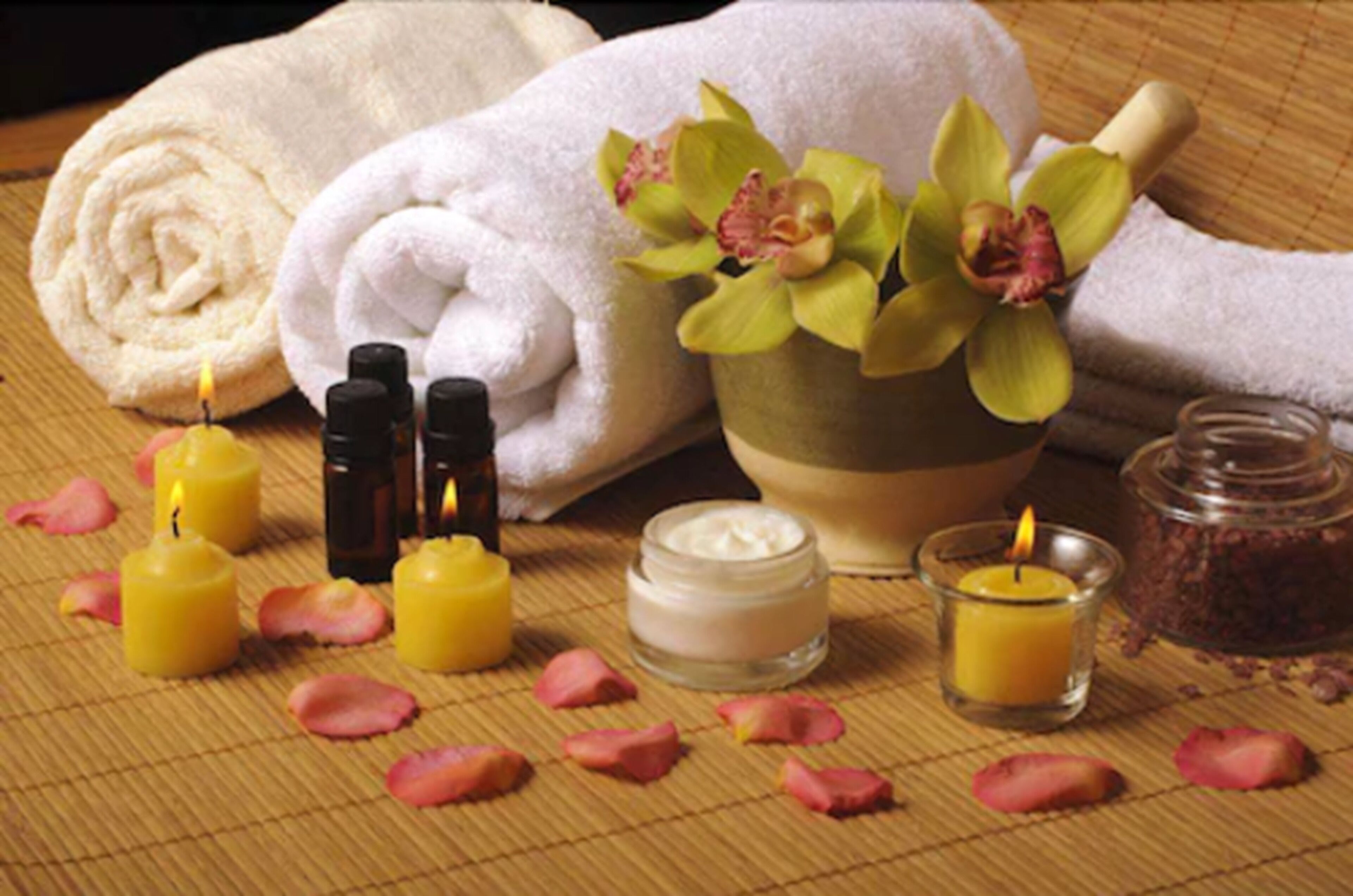 Un ambiente de spa con toallas, velas y una orquídea en maceta.