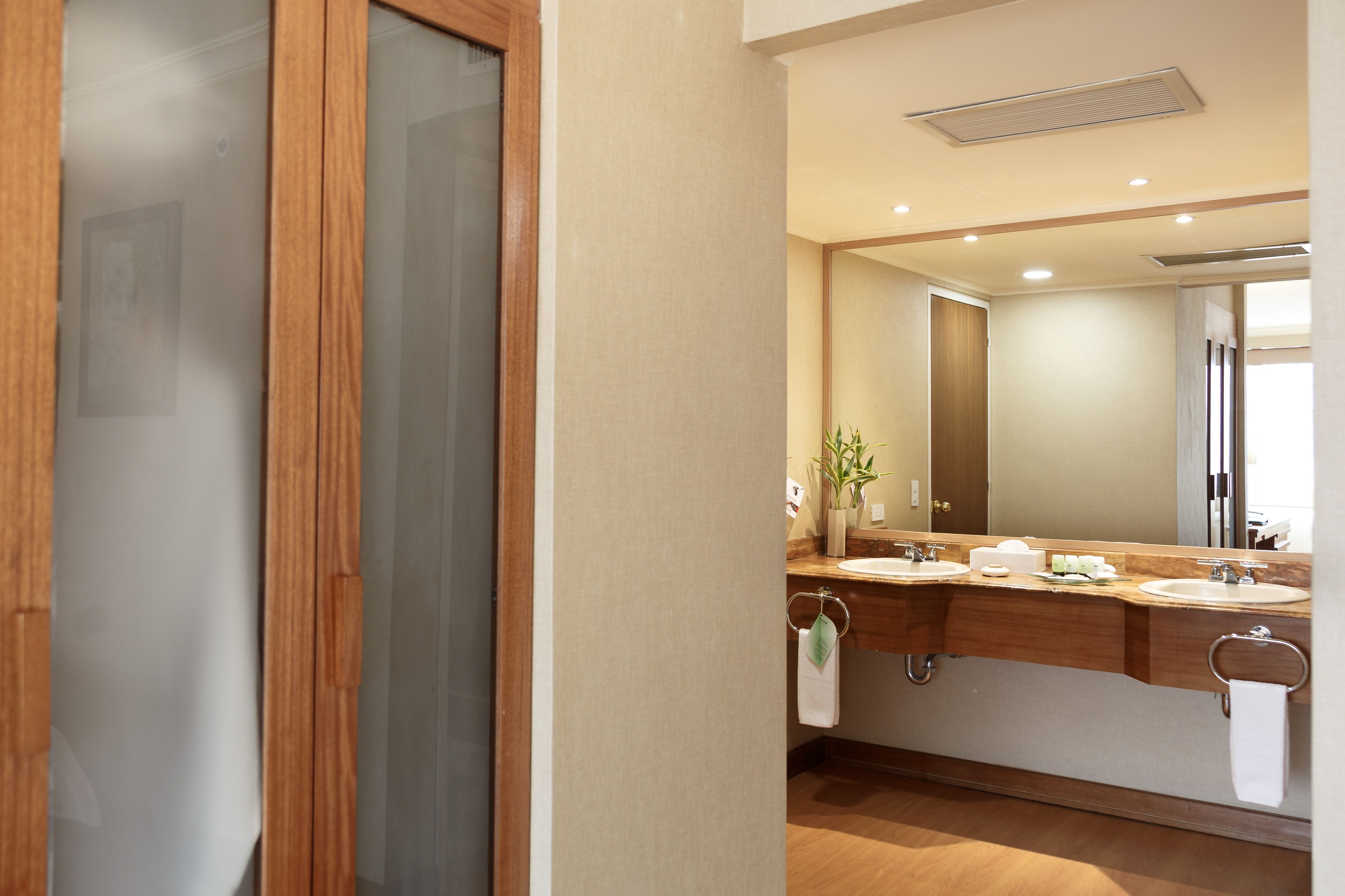 A modern bathroom with two sinks, a large mirror, and a wooden vanity.
