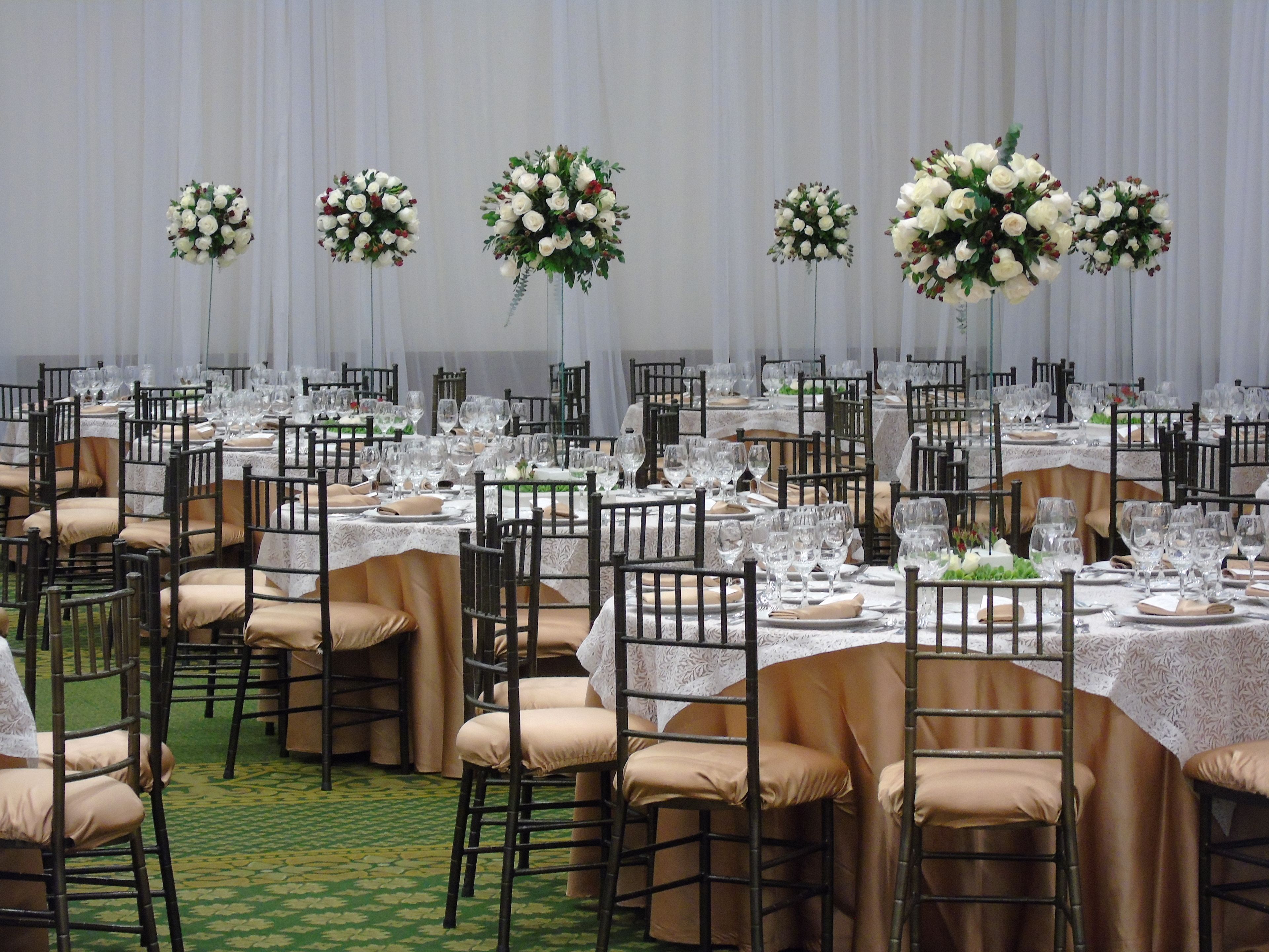 A banquet hall with round tables set for a formal event, complete with chairs, glassware, and floral centerpieces.