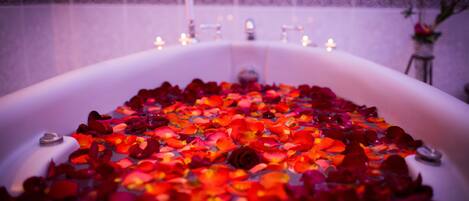 A bathtub filled with rose petals and candles.