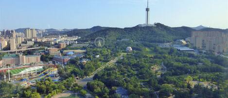 A cityscape with a prominent tower, a large Ferris wheel, and a park area with pathways and greenery.