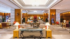 A spacious lobby with a central round table, comfortable seating, and a chandelier. - Ruishi Hotel Dalian (Dalian)
