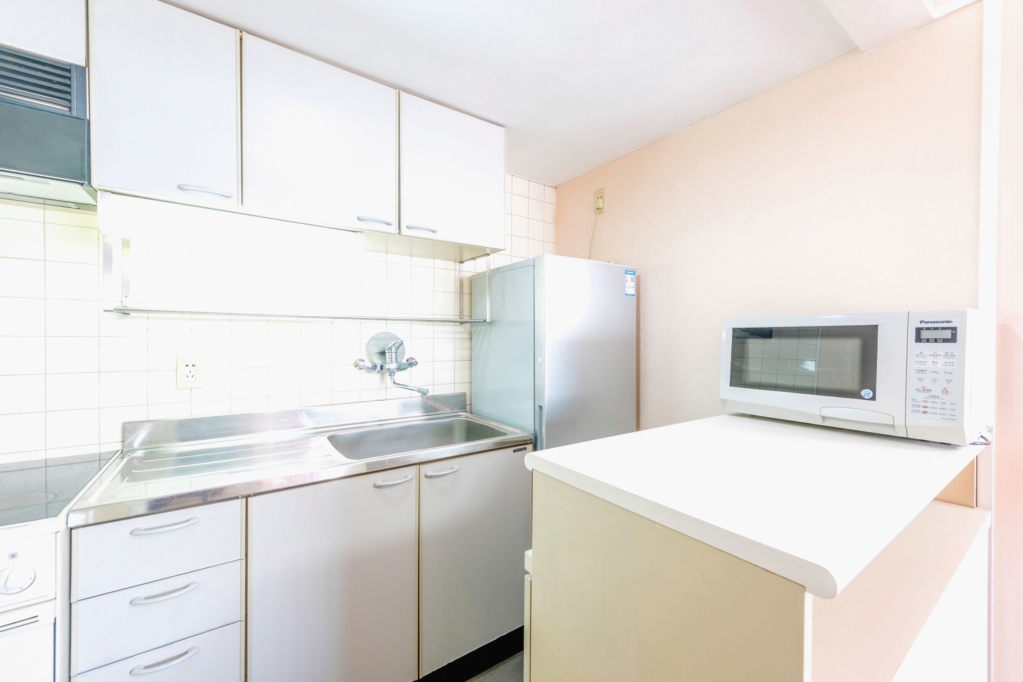 A compact kitchen with white cabinets, a stainless steel sink, and a built-in microwave.