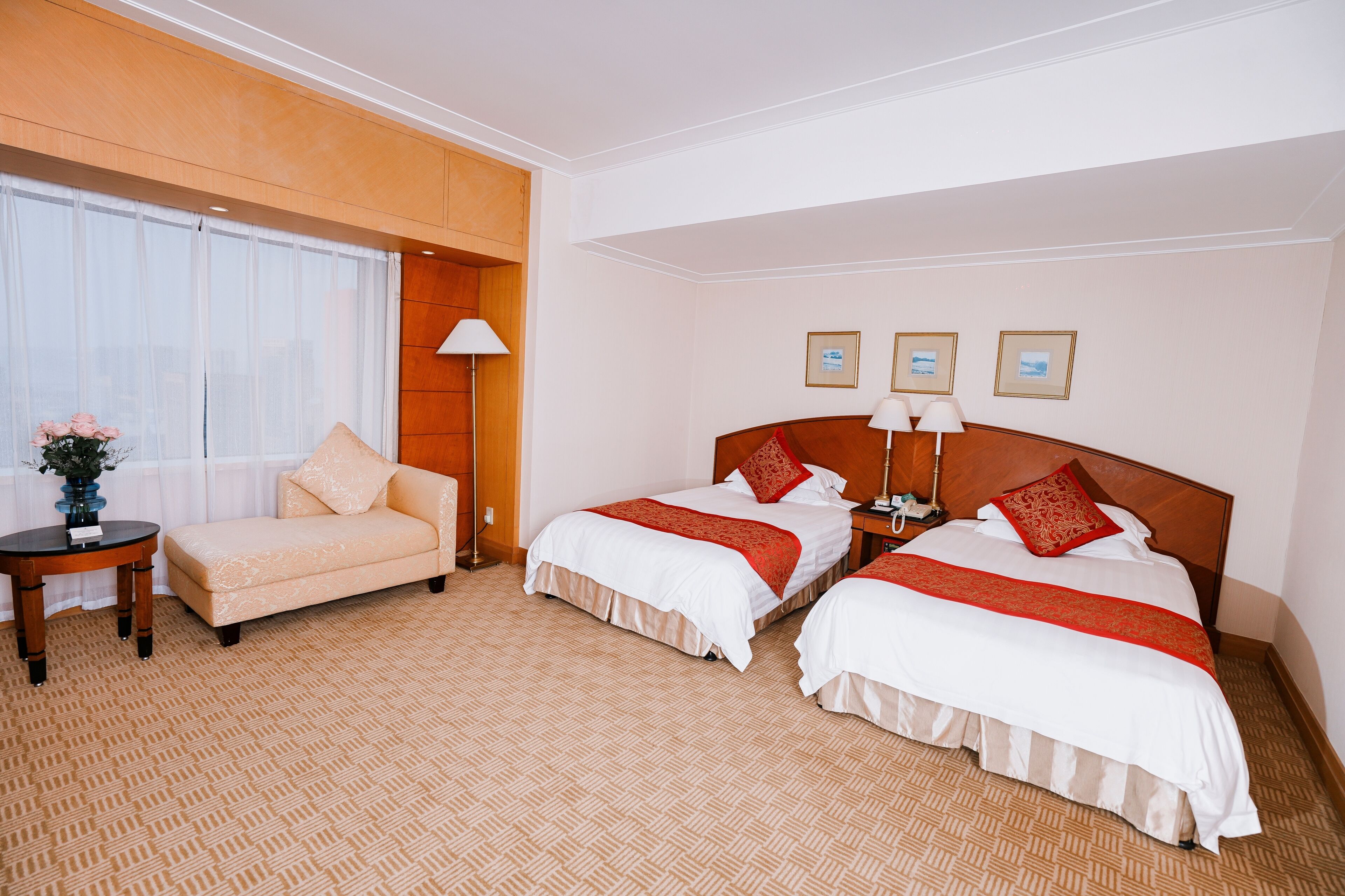A hotel room with two beds, a sofa, a small table, and a lamp.