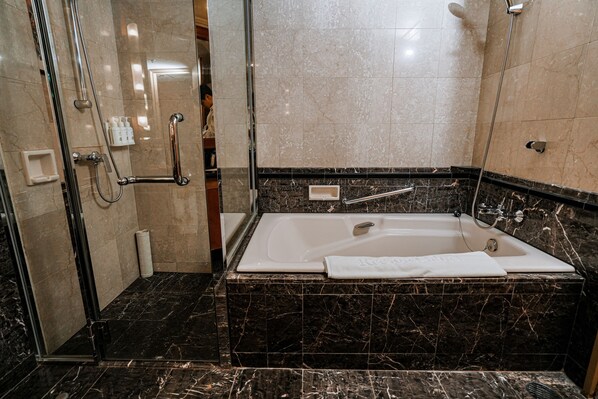 Un baño moderno con una bañera grande, una ducha con cerramiento de vidrio y suelo de mármol.