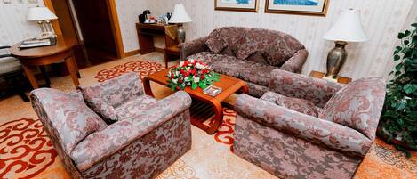 Un salón con sofás estampados, una mesa de centro con un arreglo floral y una alfombra de diseño geométrico.