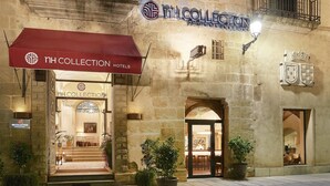 A hotel entrance with a red awning, a sign for 'NH COLLECTION Hotels', and a stone facade. - NH Collection Cáceres Palacio de Oquendo (Cáceres)
