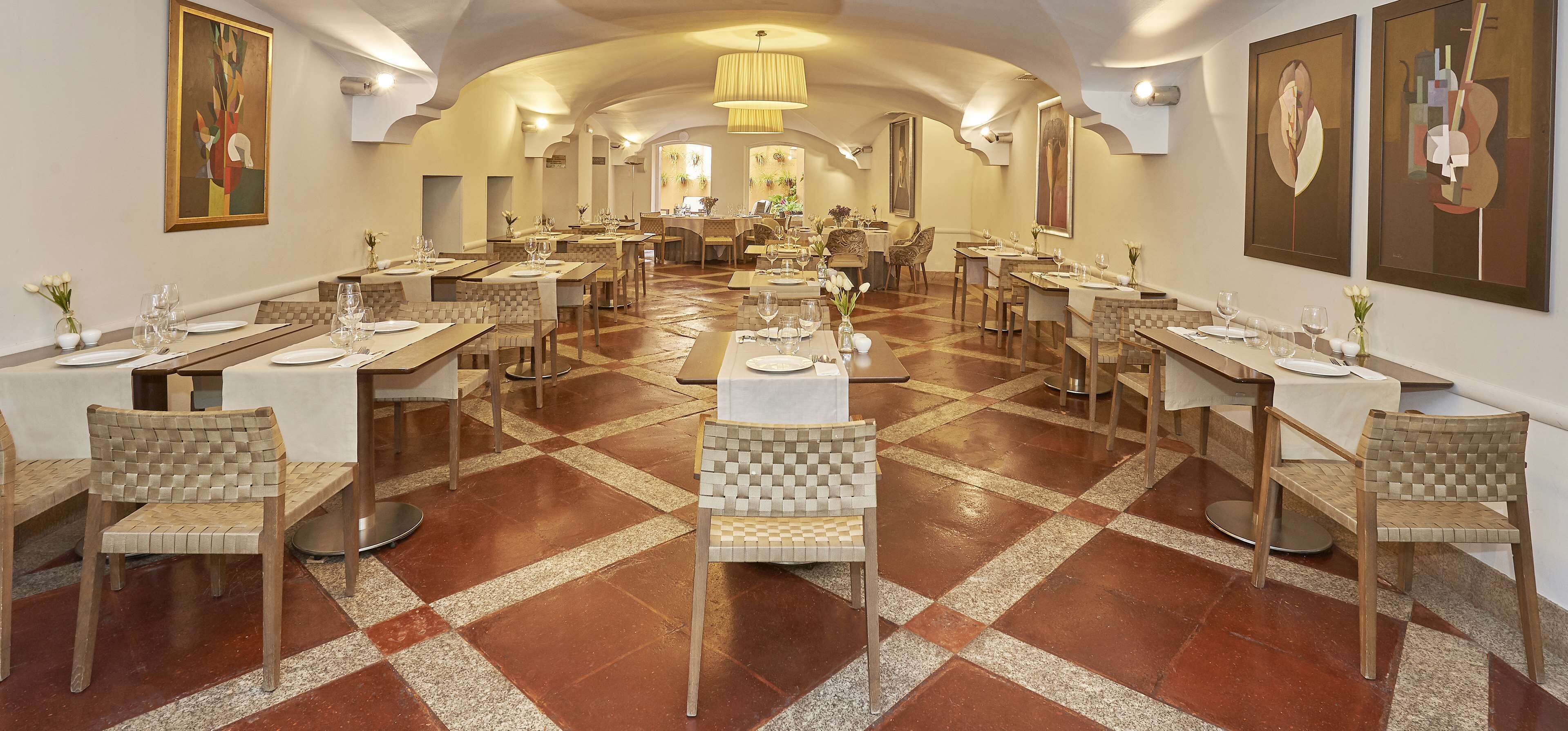 Un restaurante amplio con varias mesas y sillas, que presenta un suelo con estampado de cuadros y una decoración moderna.