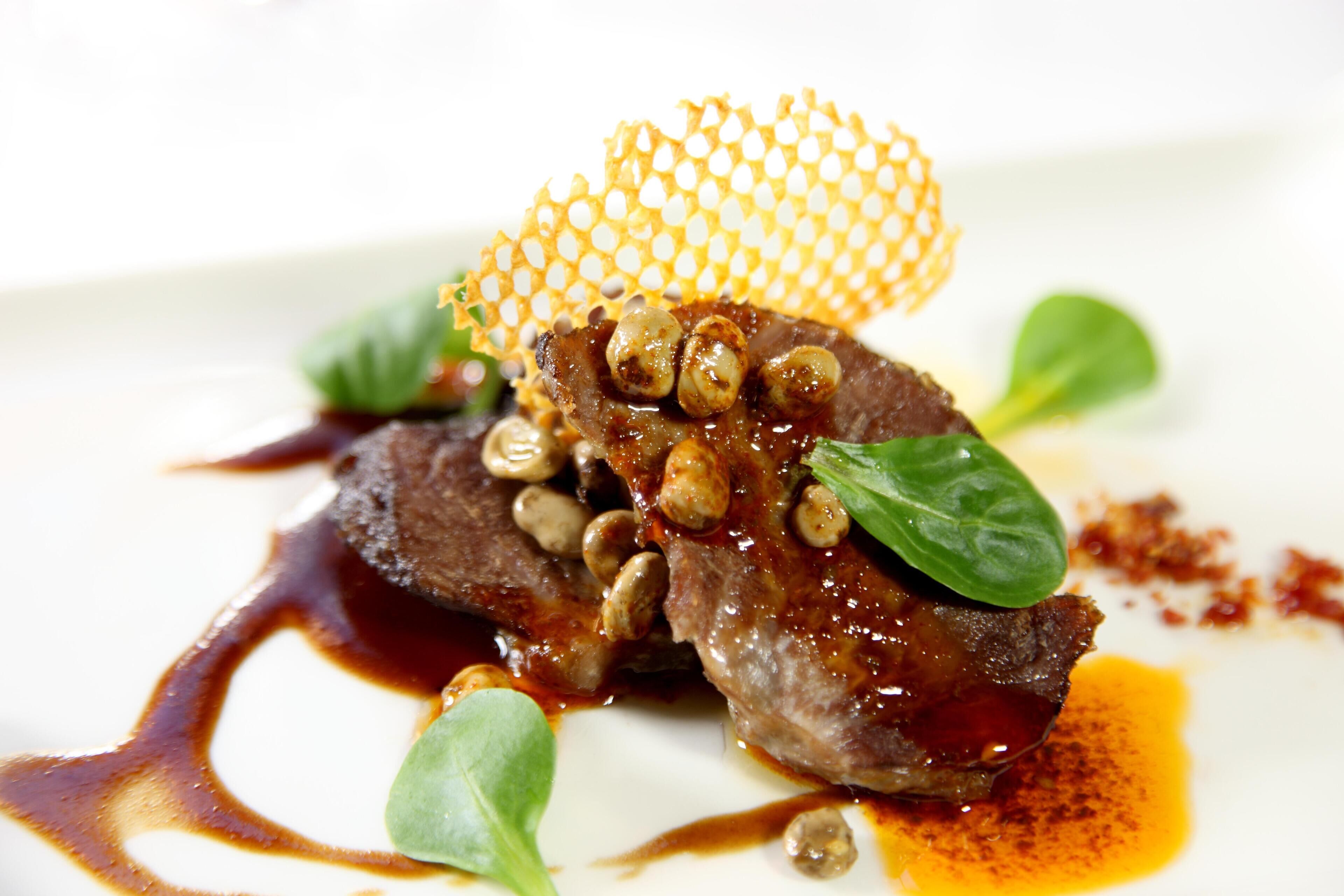 Un plato con carne, champiñones y verduras verdes.