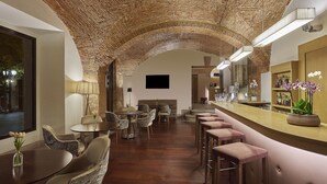 A bar area with a stone arch, seating, and a bar counter with a plant. - NH Collection Cáceres Palacio de Oquendo (Cáceres)