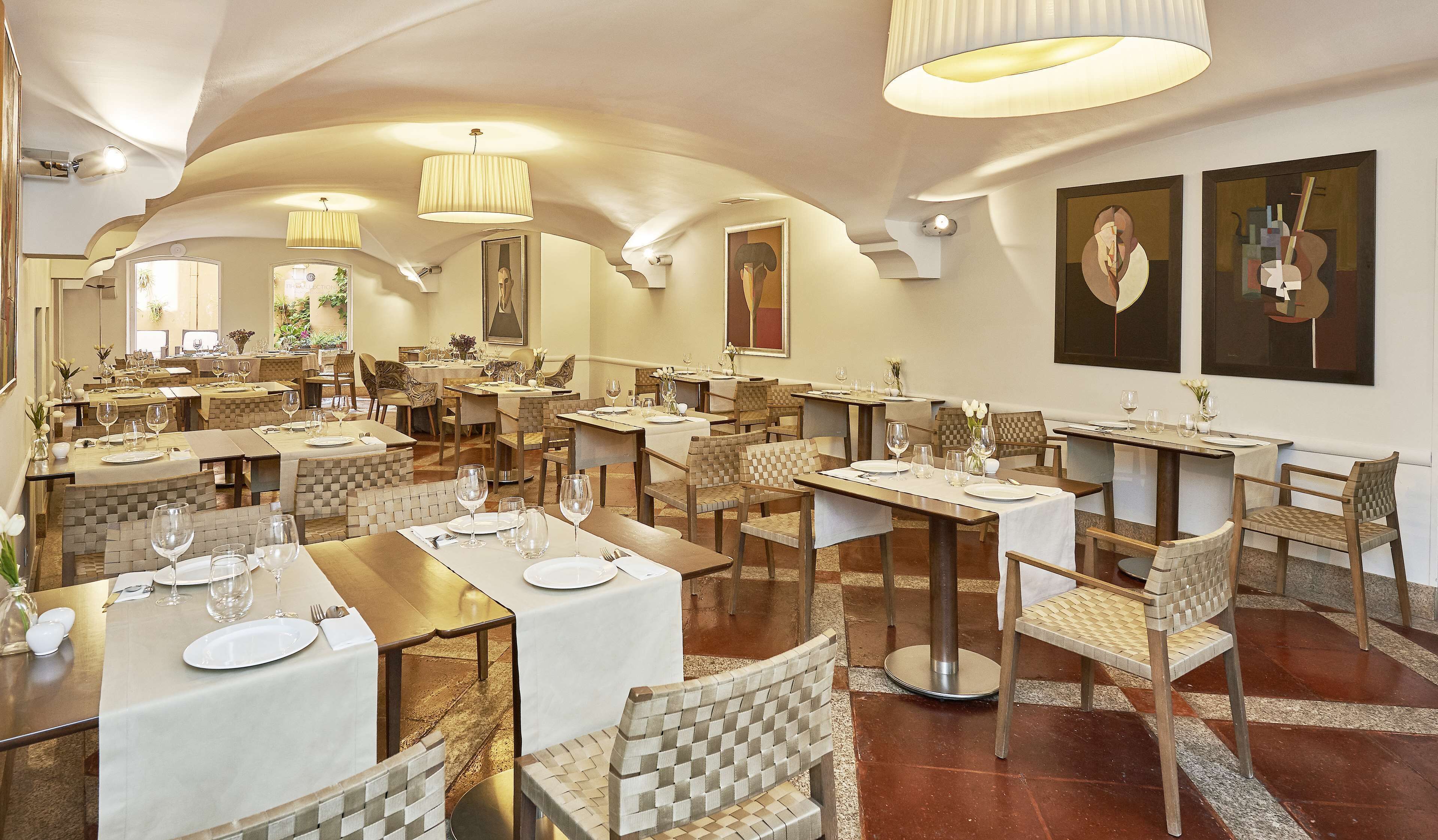 Un restaurante con varias mesas, sillas e iluminación colgante.