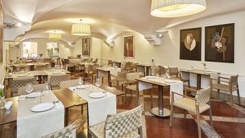 Un restaurante con varias mesas, sillas e iluminación colgante.
