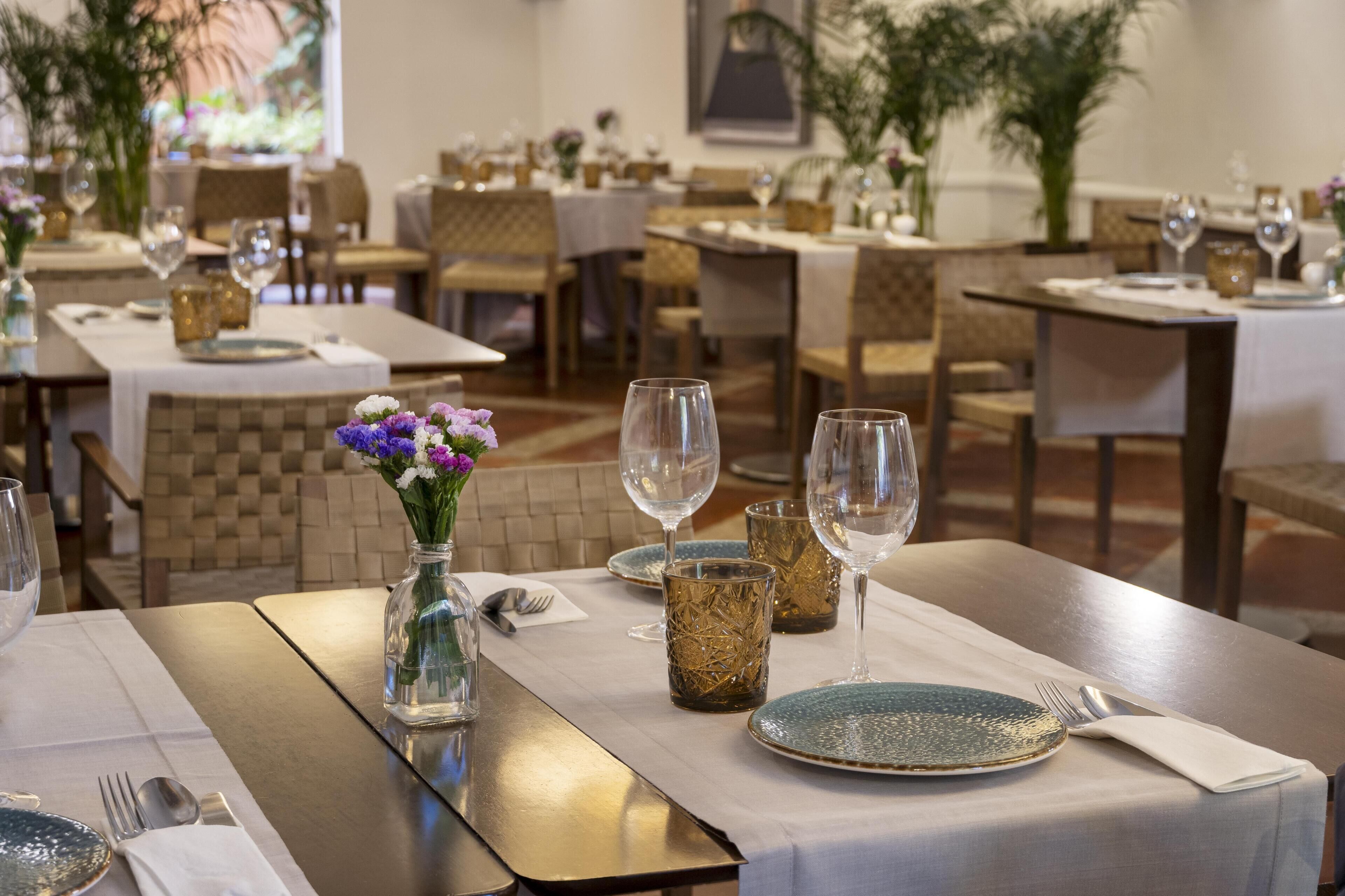 A restaurant with tables set for dining, featuring clear glassware and decorative vases.