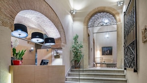 A hotel lobby with a reception desk, a staircase, and a seating area. - NH Collection Cáceres Palacio de Oquendo (Cáceres)