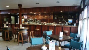 A restaurant interior with wooden bar stools, tables, and chairs. - Hotel El Hidalgo (Valdepenas)