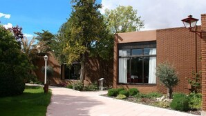 A modern building with a brick facade, large windows, and a paved walkway. - Hotel El Hidalgo (Valdepenas)