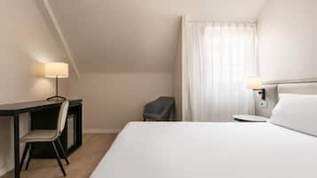 Habitación de hotel con cama, escritorio, silla y dos lámparas de noche.