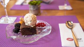 A dessert plate with a scoop of ice cream, a piece of cake, and berries on a purple placemat.