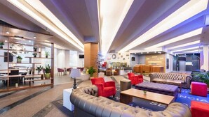 A modern hotel lobby with a central seating area, a reception desk, and a staircase leading to upper floors. - Exe Coruña (A Coruña)