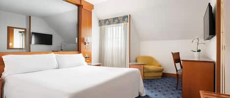 A hotel room with a large bed, a desk, a chair, a television, and a window with curtains.