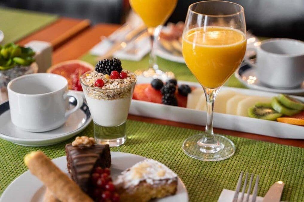 Una escena de desayuno con diferentes platos, un vaso de zumo de naranja y una taza de café.