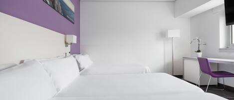 A modern hotel room with a large bed, a desk with a chair, a flat-screen TV, and a painting on the wall.