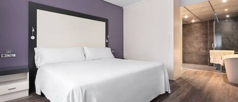 Un dormitorio moderno con una cama grande, un vestidor y un baño con cabina de ducha de vidrio.
