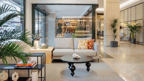 A modern lobby with a sofa, a round table, and a bookshelf.