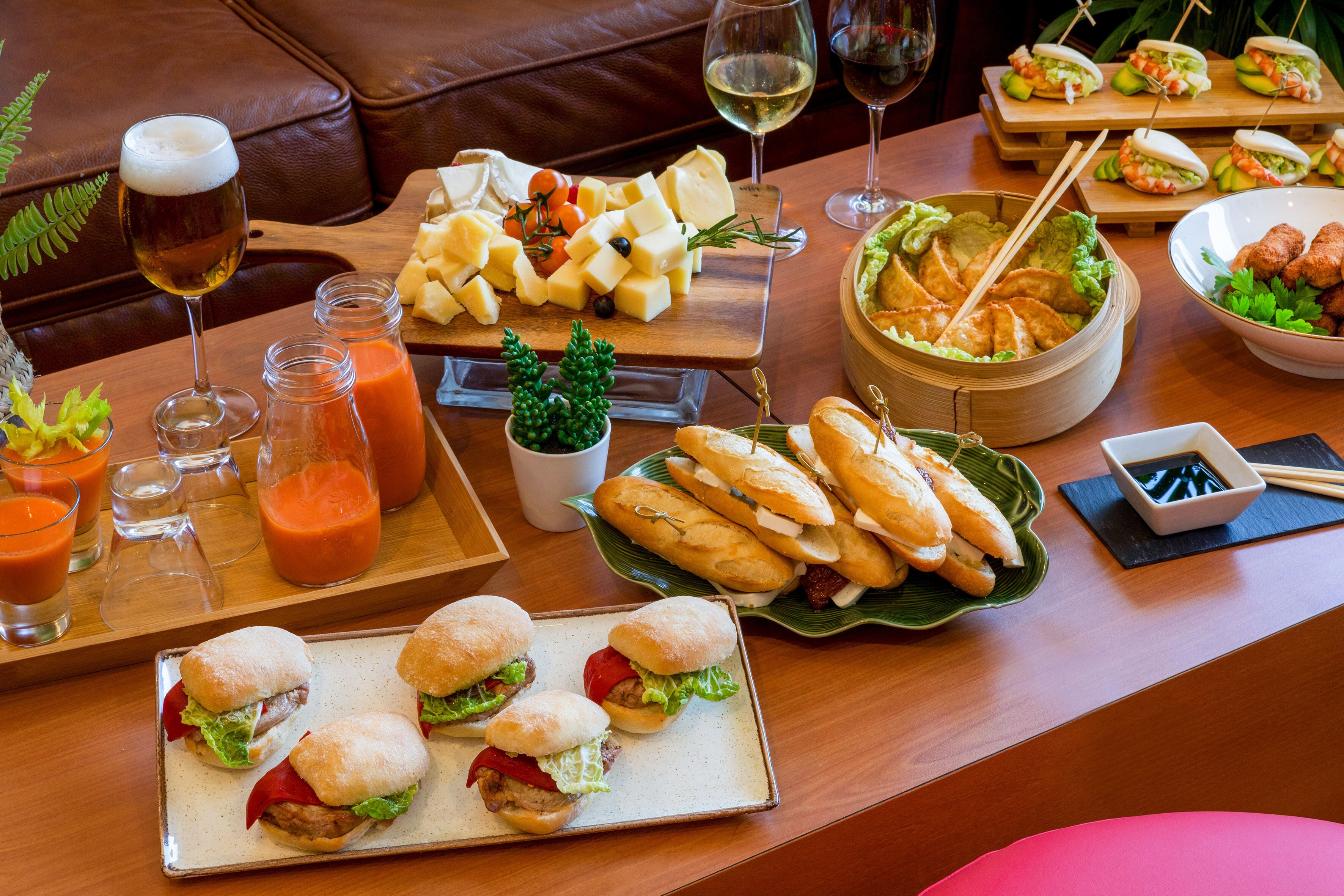 Uma mesa de jantar com diversos alimentos, incluindo sanduíches, queijo e uma tigela de sopa.