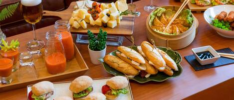 A dining table with various food items, including sandwiches, cheese, and a bowl of soup.