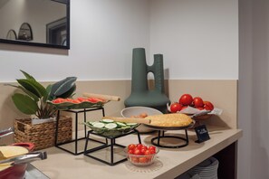 Montaje de bufé con diferentes opciones de comida, incluyendo una ensalada, tomates y una tarta.
