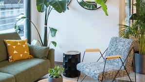 A modern living room with a sofa, a patterned armchair, a round wooden coffee table, and large mirrors on the wall.